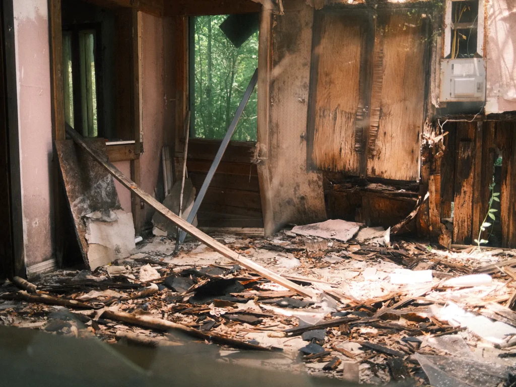 A room damaged by fire, with charred wood and debris on the floor