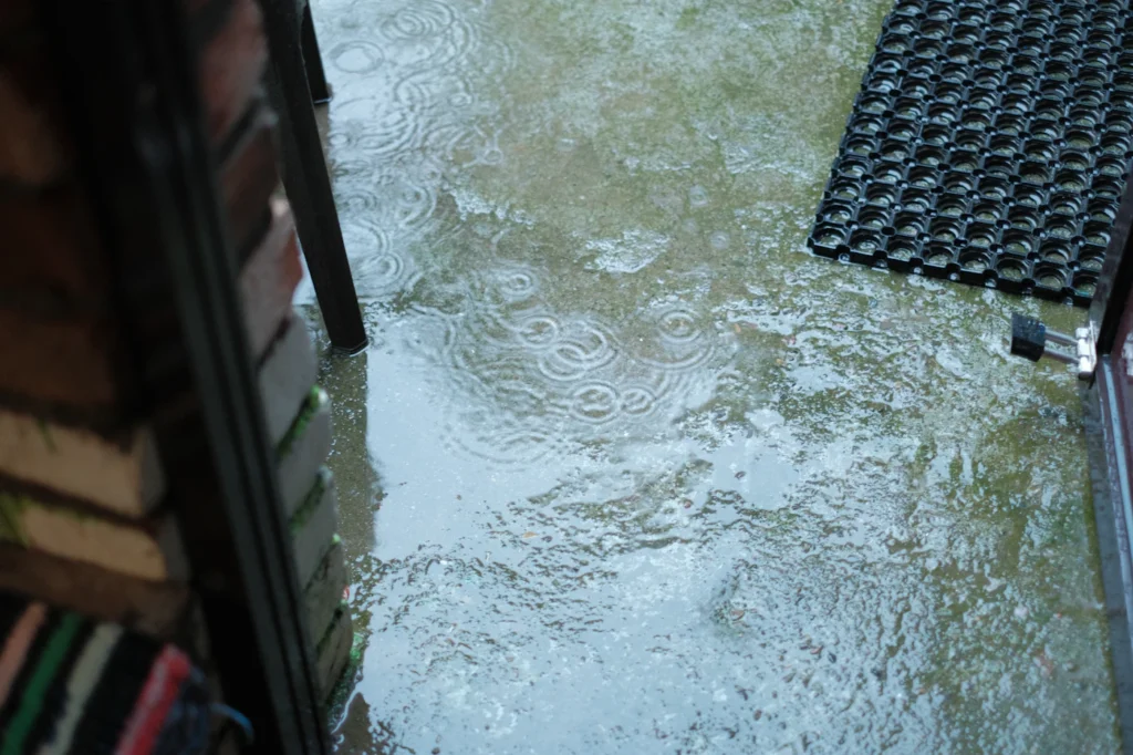 Standing rainwater pooled at a doorway, the kind of water intrusion that needs fast extraction